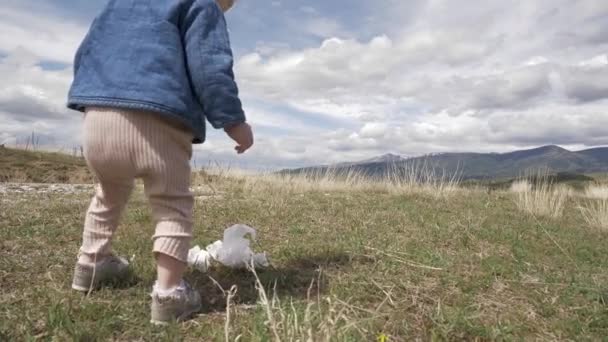 Kleines blondes Mädchen sammelt Müll in der Natur, Gesellschaft gegen Umweltverschmutzung — Stockvideo