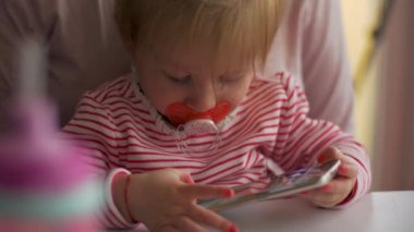 Telefonla oynayan emzikli küçük bir kız.