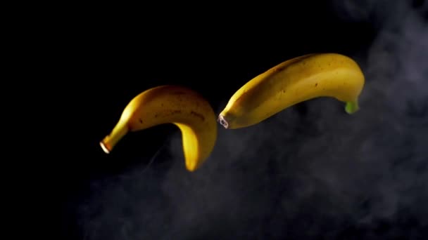 Lançamento de bananas. Fundo preto fumado. Movimento lento — Vídeo de Stock