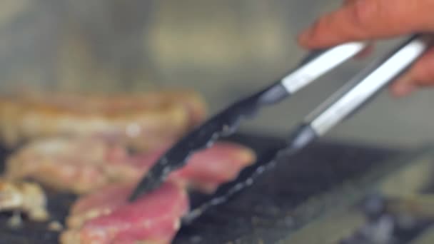Tourner la viande sur le gril à l'extérieur — Video