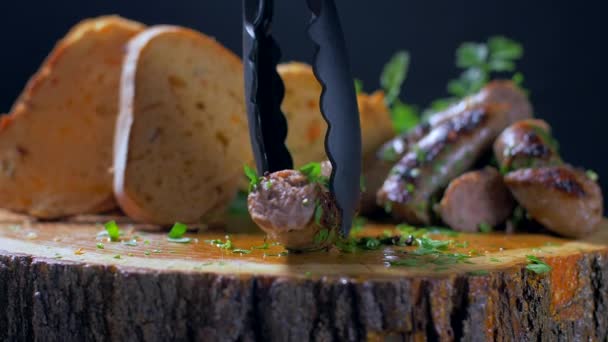 Резка сочных жареных колбас с ножом на деревянной доске — стоковое видео