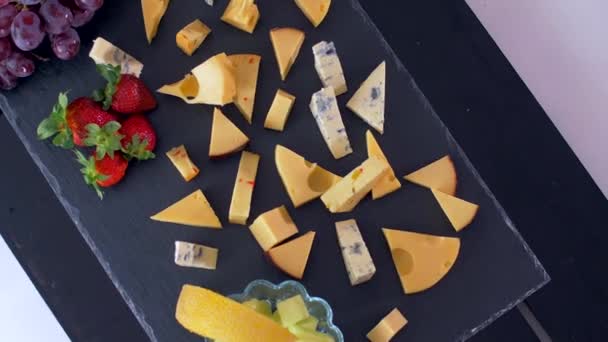 Різні види сирів на чорному камені виглядають дуже апетитно — стокове відео