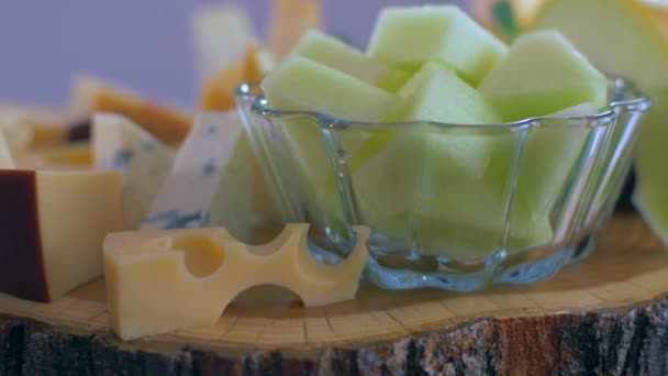 Different types of cheeses on a wooden board are rotating in a circle — Stock Video