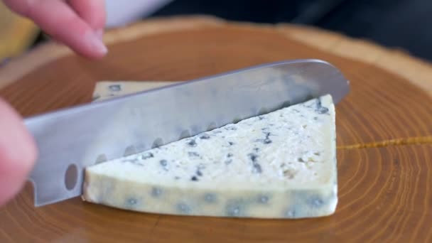 Řezání modrého sýra nožem na dřevěné desce — Stock video