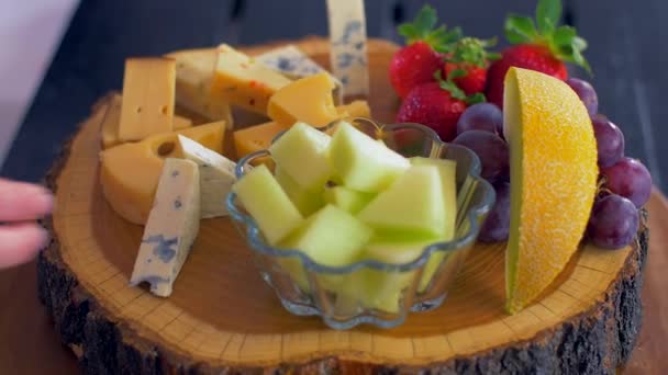 Размещение различных видов сыра на деревянной доске — стоковое видео