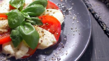 Güzel siyah bir arka plan üzerinde salata Caprese düzenlenmiştir. Yemeğinizin tadını çıkarın