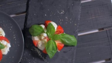 Güzel siyah bir arka plan üzerinde salata Caprese düzenlenmiştir. Yemeğinizin tadını çıkarın