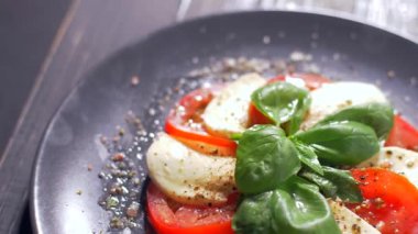 Güzel siyah bir arka plan üzerinde salata Caprese düzenlenmiştir. Yemeğinizin tadını çıkarın