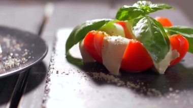 Güzel siyah bir arka plan üzerinde salata Caprese düzenlenmiştir. Yemeğinizin tadını çıkarın