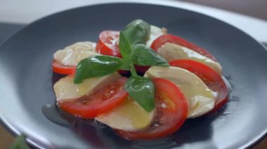 Güzel siyah bir arka plan üzerinde salata Caprese düzenlenmiştir. Yemeğinizin tadını çıkarın