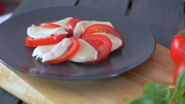 Caprese Salatası'na fesleğen ekliyor. Siyah arka plan