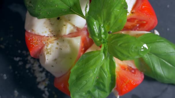Gyönyörűen elrendezett saláta Caprese fekete háttérrel. Étkezzen — Stock videók