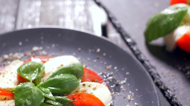 Ensalada bellamente arreglada Caprese sobre un fondo negro. Disfrute de su comida — Vídeos de Stock