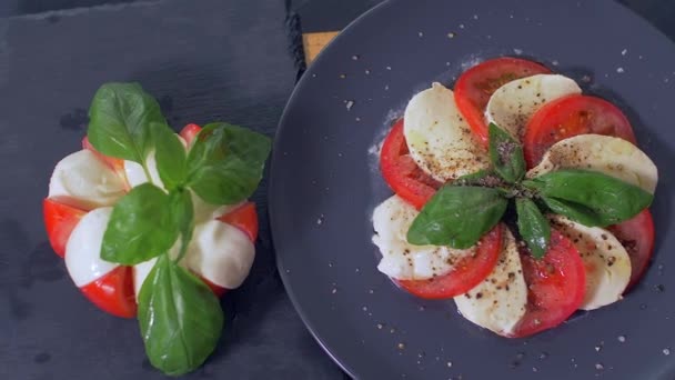 Güzel siyah bir arka plan üzerinde salata Caprese düzenlenmiştir. Yemeğinizin tadını çıkarın — Stok video