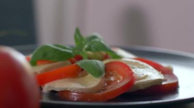 Caprese salatasının üzerine zeytinyağı döküldü. Siyah arka plan