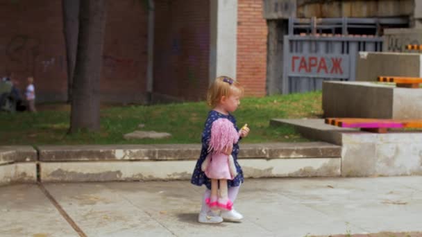 Egy kis szőke lány kék ruhában élvezi a galambokat — Stock videók