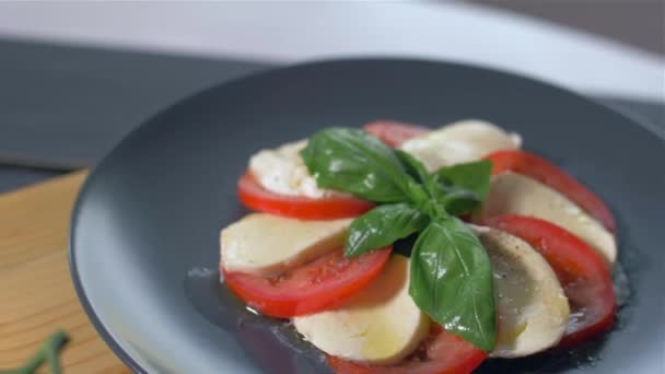 Añadir especias a la ensalada Caprese. Fondo negro — Vídeos de Stock