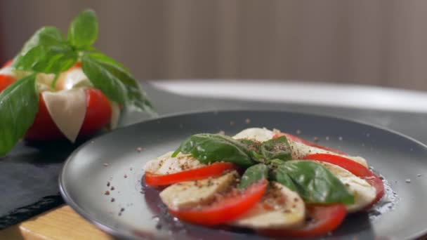 Ensalada bellamente arreglada Caprese sobre un fondo negro. Disfrute de su comida — Vídeos de Stock