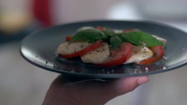 Siyah bir arka plan üzerinde salata Caprese hizmet vermektedir. Çok iştah açıcı