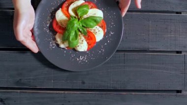 Siyah bir arka plan üzerinde salata Caprese hizmet vermektedir. Çok iştah açıcı