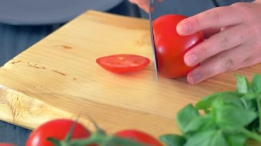 Ahşap kesme tahtasıüzerinde domates kesme eller 