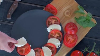 Siyah tabakta caprese salatası hazırlanması. Siyah arka plan 