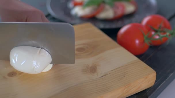 Tangan memotong keju mozzarella di papan potong kayu — Stok Video