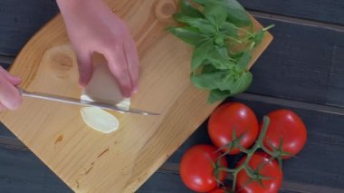 Ahşap kesme tahtası üst te mozzarella peyniri kesen eller