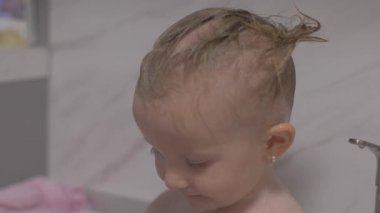 Çekici iki yaşındaki kız banyo alır. Anne bir şampuan ile saç temiz.