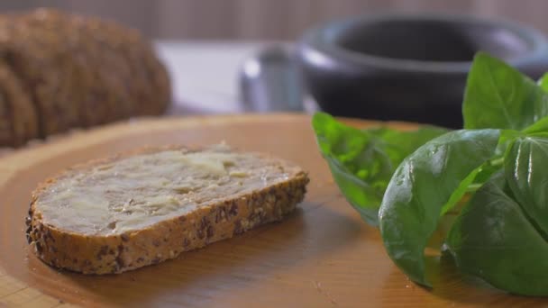 Рука намазала масло на кусок цельнозернового хлеба на деревянную доску — стоковое видео