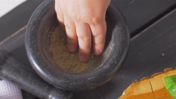 Een vrouwelijke hand neemt specerijen van de mortel — Stockvideo