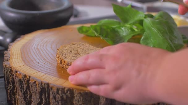 El, tahta bir tahtaüzerine tam tahıllı bir ekmek parçasına yağ serpiştir. — Stok video