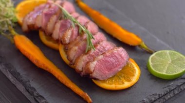 Turuncu bir kanepede ördek göğüslerinden oluşan bir tabak. İyi pişmiş ördek.