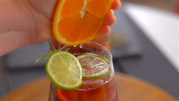 Squeezing an orange in a cocktail sangria. Very juicy — Stock Video