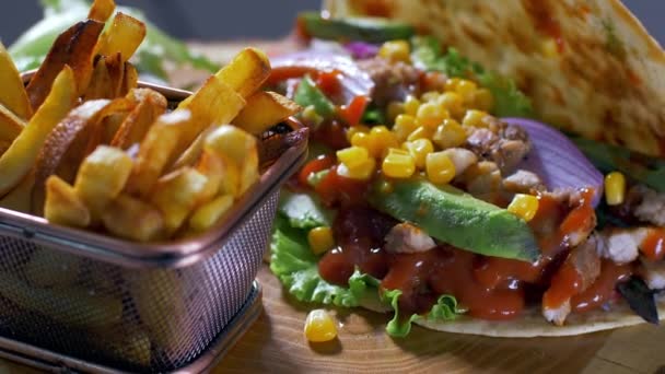 Delicioso burrito de comida mexicana y papas fritas servidas en una tabla de madera — Vídeo de stock