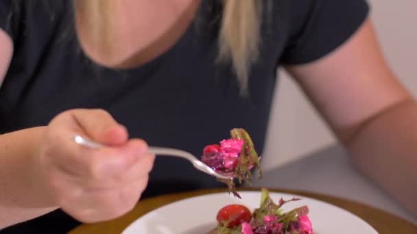Übergewichtige Frau zu Hause isst Gemüsesalat in der Küche. — Stockvideo