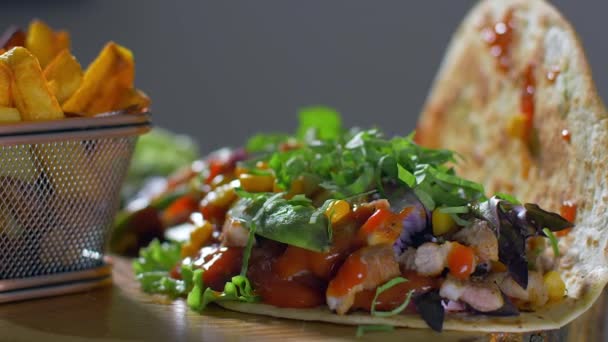 Heerlijk Mexicaans eten burrito en gebakken aardappelen geserveerd op een houten plank — Stockvideo