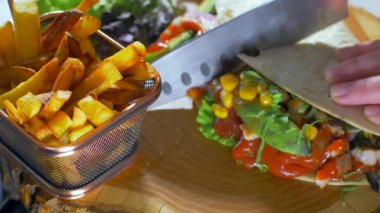 Kadın, bir bıçak Meksika gıda bir burrito ahşap bir tahta üzerinde servis ile keser