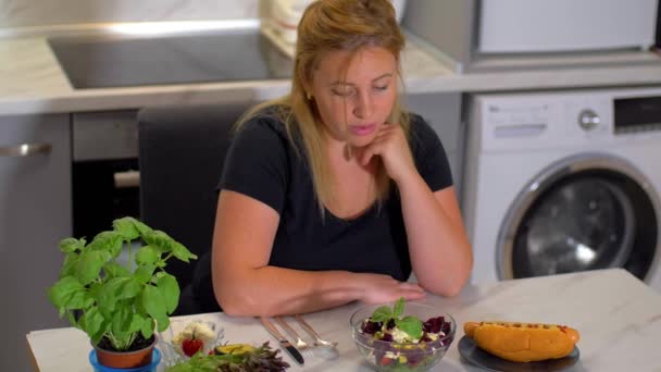 Жінка своїми руками вибирає тарілку салату і відмовляється від тарілки хот-догів  . — стокове відео