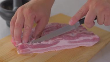 Şef ahşap tahtada keskin bir bıçakla çiğ domuz pastırması keser.