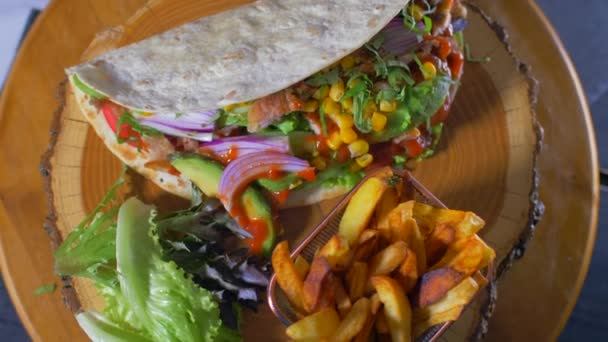 Ízletes mexikói élelmiszer-burrito és sült burgonya szolgált egy fából készült hajón — Stock videók