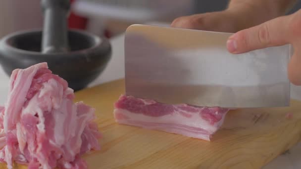 Chef cuts pieces of raw bacon by sharp knife on the wooden board — Stock Video