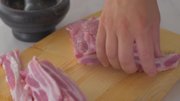 Chef corta trozos de tocino crudo con un cuchillo afilado en la tabla de madera — Vídeo de stock