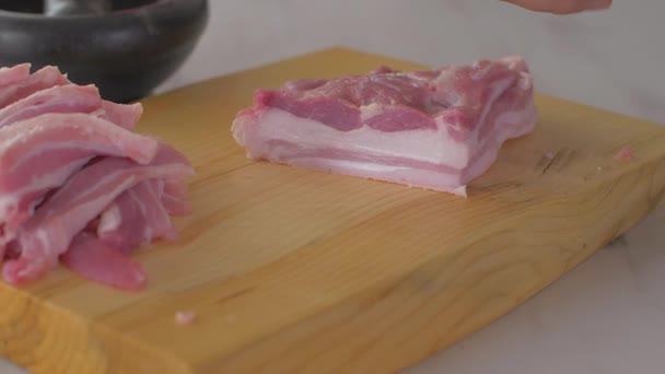 Chef corta pedaços de bacon cru por faca afiada na placa de madeira — Vídeo de Stock