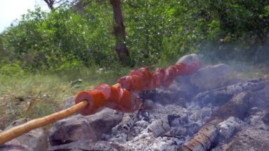 Doğada çubuklar üzerinde sosis kavurma. Yangın yanıyor