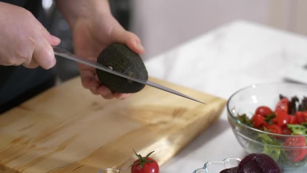 Ženská ruka řeže avokáda o její zdravý salát — Stock video