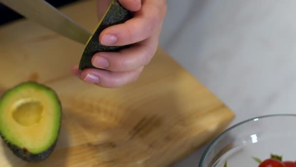 En kvinnlig hand nedskärningar avokado o för hennes friska sallad — Stockvideo