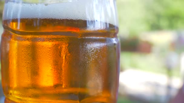 A glass of beer close up in a park — Stock Video