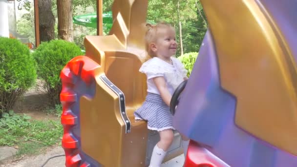 Jolie petite fille souriante balançant sur une balançoire dans la journée d'été. Mouvement lent . — Video