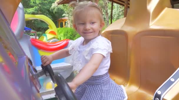 Schattige lachende babymeisje swingen op een schommel in de zomerdag. Slow motion. — Stockvideo